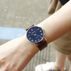 Close-up of a blue dial quartz watch with Roman numerals and brown leather strap on wrist