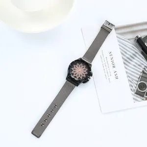 Elegant ladies watch with flower dial and grey mesh band on a minimalist background