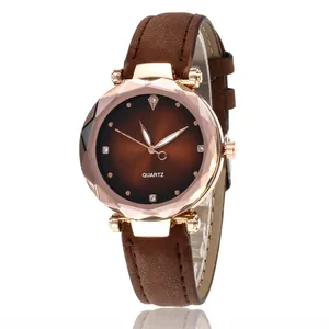 Détail d'une montre à quartz or rose avec lunette géométrique et bracelet en cuir brun