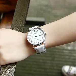 Close-up of white quartz watch with Roman numerals and leather strap on wrist
