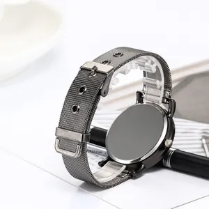 Detail of grey stainless steel watch back and adjustable Milanese mesh band on a desk