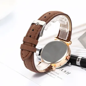 Détail du bracelet en cuir suédé marron et boîtier en or rose d'une montre à quartz
