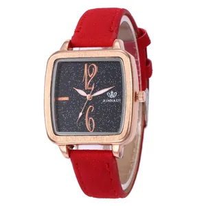 Close-up of square rose gold watch with starry black dial and red suede leather strap