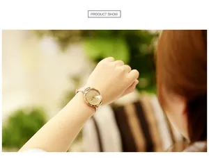 Détail de montre élégante pour femme avec cadran doré pailleté et bracelet en cuir rose