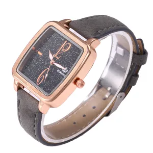 Macro view of square quartz watch with rose gold case and gray strap on white base