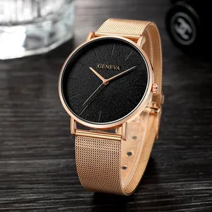 Minimalist black dial quartz watch with rose gold mesh strap on a dark wooden background