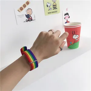 Bracelet arc-en-ciel en nylon tressé avec boucle ajustable porté avec des bagues