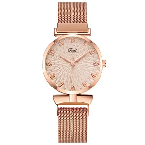 Detail of rose gold Tadi watch dial with textured relief and Milanese mesh band