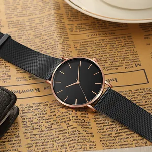Minimalist quartz watch with black mesh strap and rose gold markers on vintage newspaper
