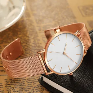 Detail shot of minimalist rose gold watch with white dial and mesh strap on leather