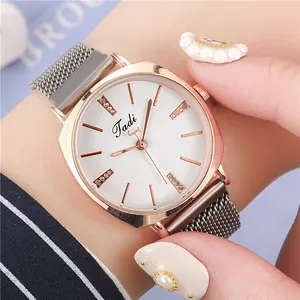Close-up of rose gold tonneau watch with white sunray dial and mesh magnetic strap