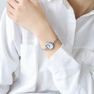 Detailed view of women's silver bangle watch with quartz movement on model's wrist