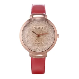 Détail du bracelet en cuir rouge et cadran scintillant de montre à quartz rose