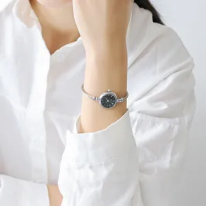 Detailed close-up of a silver cable bracelet watch for women with a black quartz dial