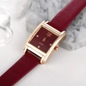 Detail einer stilvollen quadratischen roségoldenen Uhr mit burgunderfarbenem Lederarmband