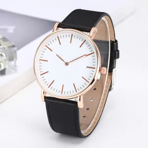Detail of rose gold quartz watch featuring a white minimalist dial and black leather strap