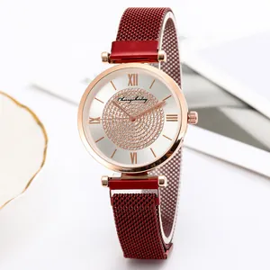 Detail of rose gold watch with rhinestone dial and burgundy mesh band on white plate
