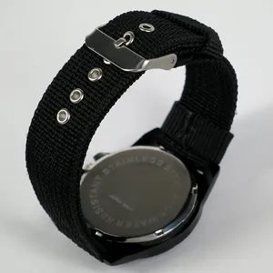 Detail of stainless steel watch back and black nylon woven strap with silver buckle