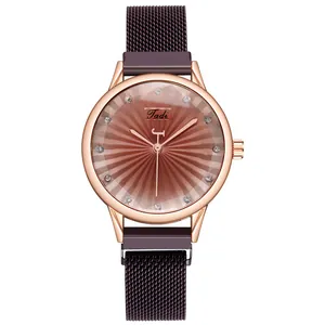 Détail d'une montre or rose avec cadran brun rayon de soleil et index en cristal