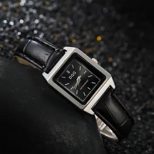 Detail einer eckigen silbernen Quarzuhr mit schwarzem Krokodillederarmband auf Stein