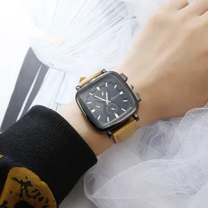 Detail of square black watch dial with golden markers and khaki leather strap