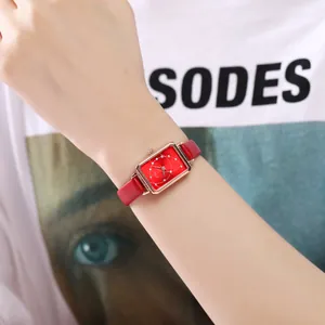 Elegant women's square red dial watch with rose gold case and leather strap on wrist