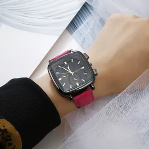 Detailed close-up of a square black dial watch with pink leather strap on a model's wrist