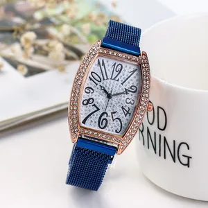 Detailopname van roségouden tonneau-horloge met kristallen en blauwe mesh band