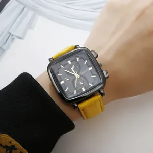 Detail of square black watch with yellow leather strap and gold hands on woman wrist
