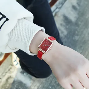 Close-up of a women's square rose gold watch with red dial and leather strap