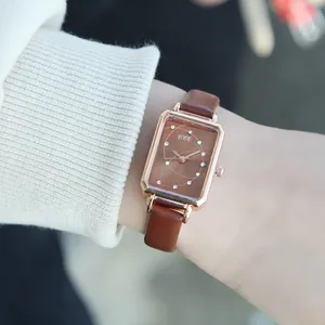 Close-up of a vintage rectangular rose gold watch with brown leather strap on wrist