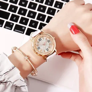 Close-up of a white leather strap watch with gold rhinestone bezel and star charm bracelet