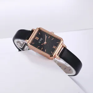 Detail of a rectangular rose gold watch with a starry black dial and leather strap