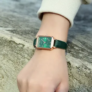 Detail of square green dial watch with rose gold case and green leather strap on wrist
