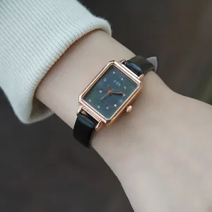 Macro view of rectangular rose gold watch with grey dial and black leather strap on wrist