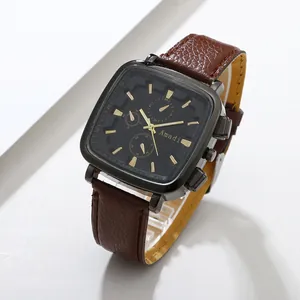 Detail of square black chronograph dial with gold hands and brown leather strap
