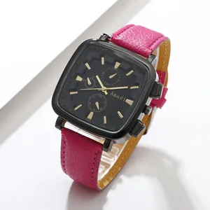 Detail of magenta leather strap and black square watch case with golden hands