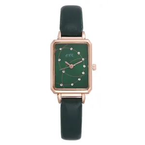 Close-up of a rectangular green watch face with gold spiral patterns and crystal markers