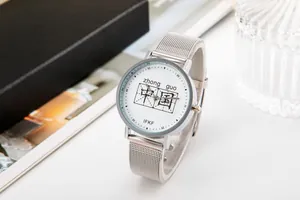 Dettaglio dell'orologio con cinturino in maglia d'argento e caratteri cinesi sul quadrante