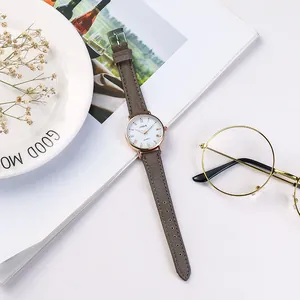 Elegante Damen Quarzuhr mit Roségold Gehäuse und grauem Wildlederarmband auf Ästhetik-Hintergrund