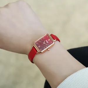 Macro shot of rectangular rose gold watch with red leather strap on woman wrist