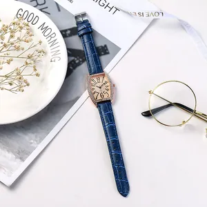 Montre bracelet cuir bleu avec boîtier tonneau or rose et cristaux sur un décor blanc