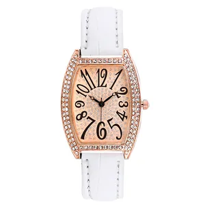 Détail d'une montre tonneau en or rose avec strass brillants et bracelet en cuir blanc