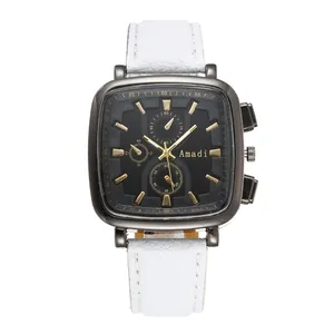 Detail of square black watch dial with gold markers and white pebbled leather strap