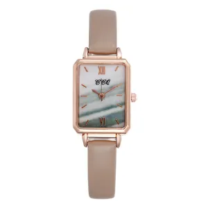 Detail of rose gold rectangular watch featuring a green marble dial and leather strap