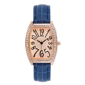 Détail du boîtier tonneau or rose avec lunette en strass et bracelet en cuir bleu