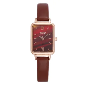 Macro detail of square rose gold watch case with brown textured gradient dial and leather strap