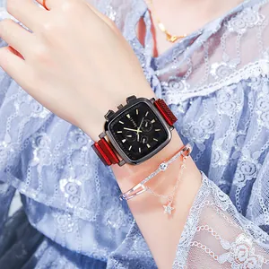 Macro shot of stylish square black dial watch with red mesh band and star charm bracelet
