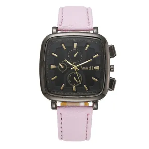 Close-up of square black watch dial with gold markers and pink textured leather strap