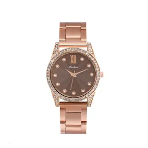 Détail d'une montre en or rose avec strass brillants et cadran marron à vagues